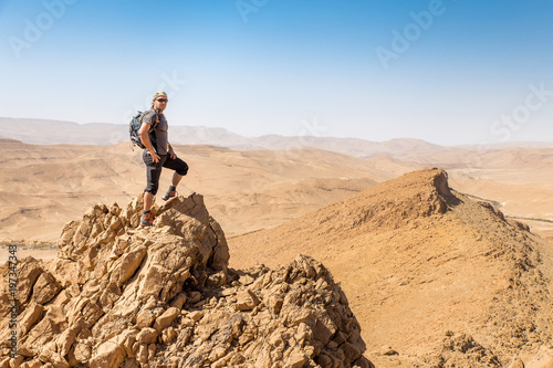 Backpacker tourist standing desert mountain cliff ridge edge landscape. © subbotsky