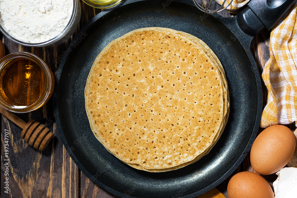 traditional thin pancakes in a frying pan and ingredients