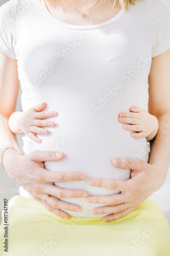 Wallpaper Mural Young pregnant woman in white t-shirt and child hands touching her stomach. Happy family concept. Torontodigital.ca