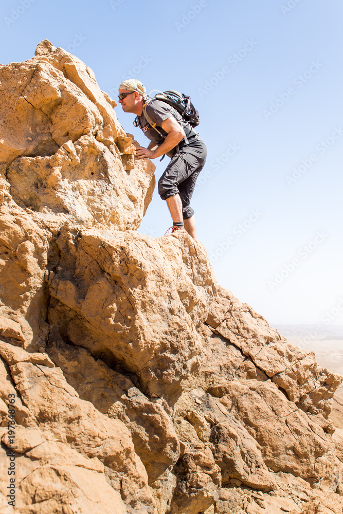 Sportsman standing desert mountain rock cliff ridge edge landscape.