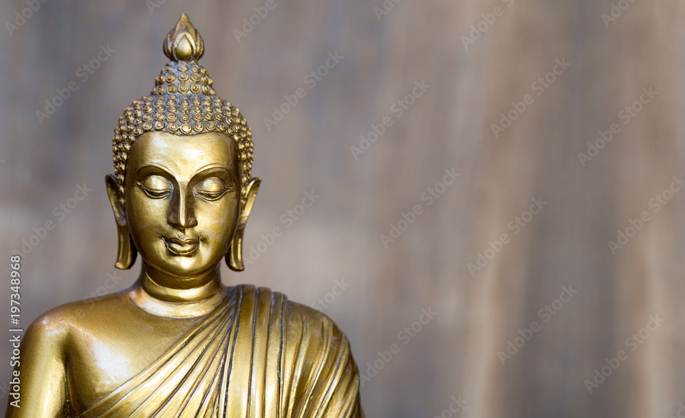 Golden antique buddha statue. The background is light slate gray. The face of the Buddha turned to the straight.