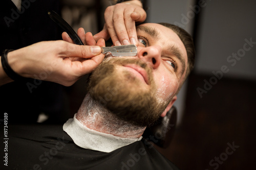 Young man having beard razor shaved