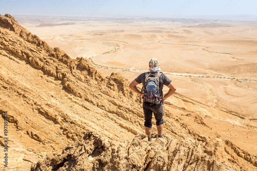 Backpacker tourist standing desert mountain cliff ridge edge landscape.
