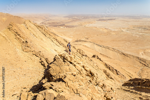 Backpacker tourist standing desert mountain cliff ridge edge landscape.