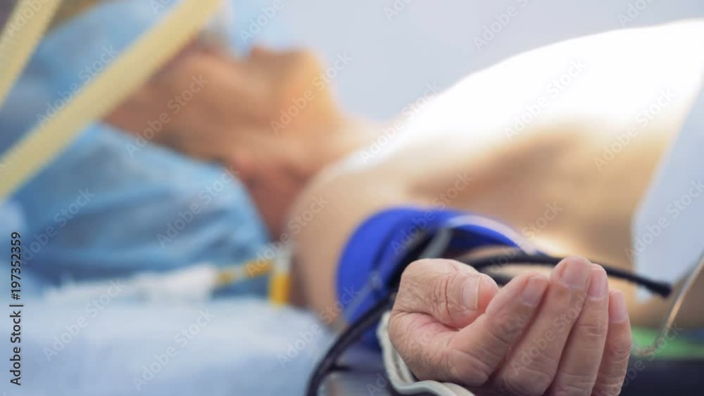 Unconscious male patient is lying on a surgical table and is getting prepared for an operation Unconscious male patient is lying on a surgical table and is getting prepared for an operation