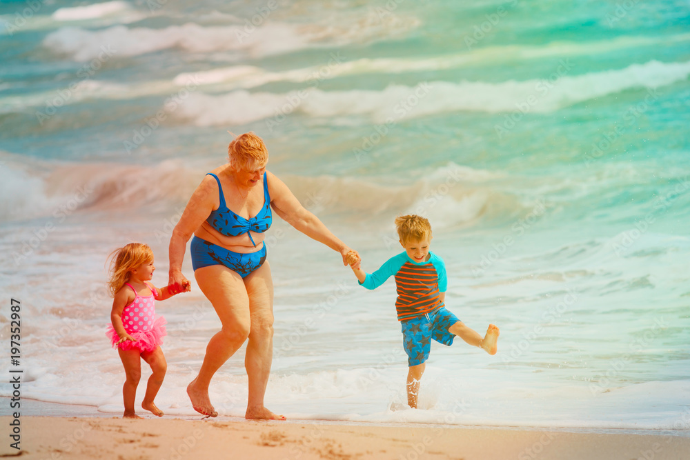 Happy grandmother with kids- little boy and girl- play on beach Happy grandmother with kids- little boy and girl- play on beach