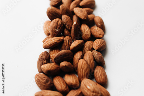 Pile of almonds on white background with copy space, healthy eating concept