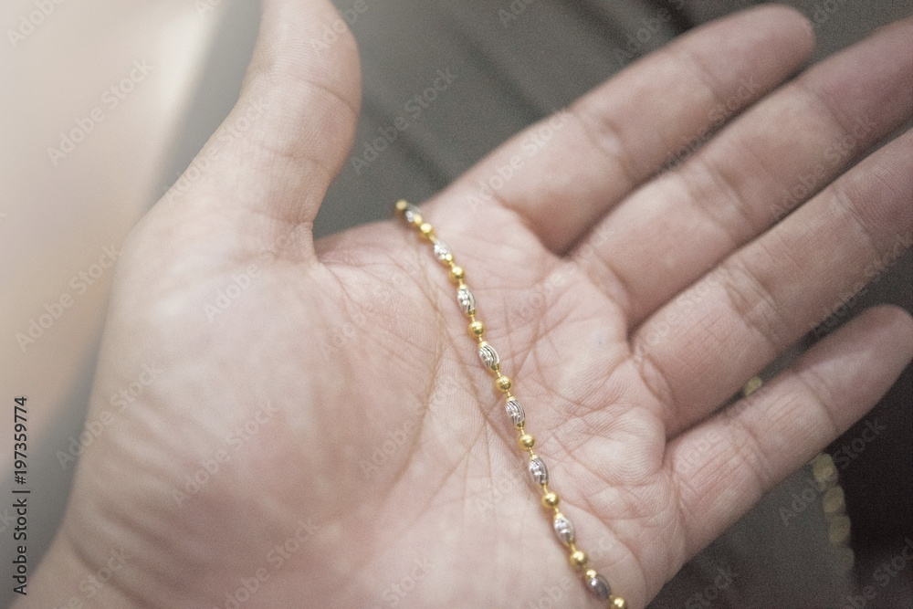 Golden necklace in human hand under the white light Golden necklace in human hand under the white light