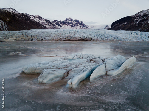 A glacier in Iceland with a frozen lake in front of it, shot with a drone photo