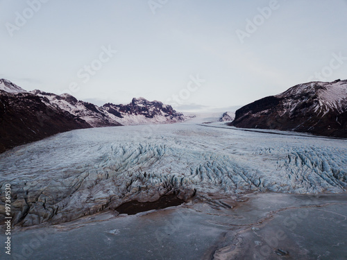 A glacier in Iceland with a frozen lake in front of it, shot with a drone photo