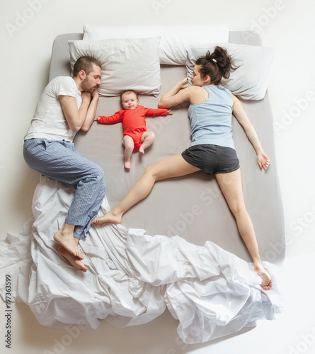 Top view of happy family with one newborn child in bedroom.