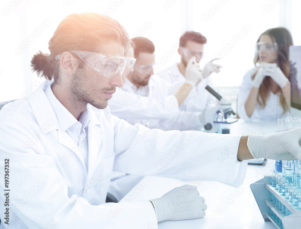 Scientists working with a microscope and make notes in the workp Scientists working with a microscope and make notes in the workp