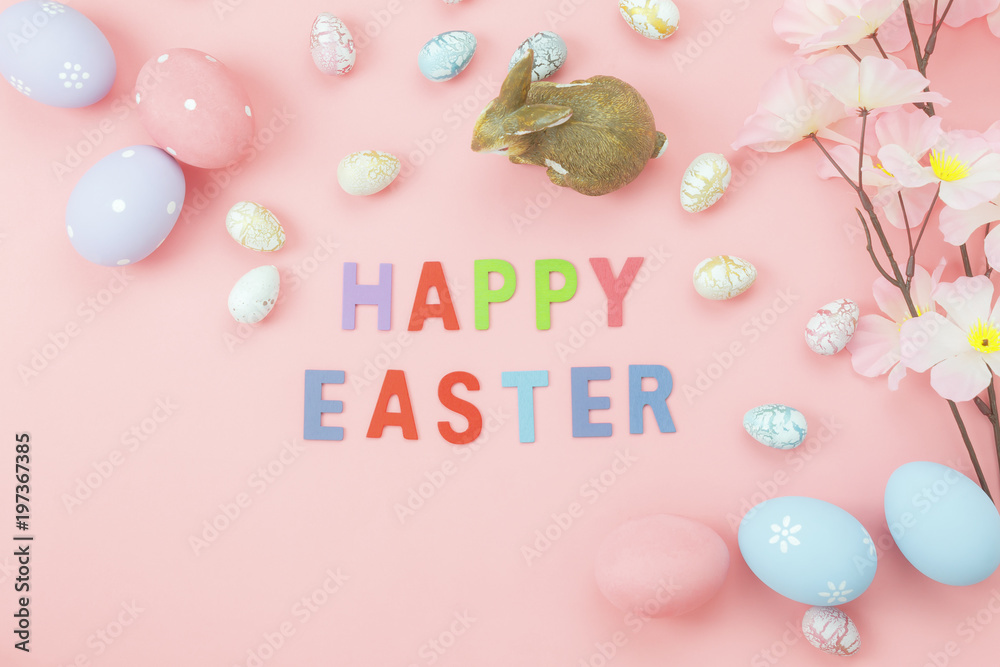 Table top view shot of arrangement decoration Happy Easter holiday background concept.Flat lay colorful bunny eggs with flower and rabbit doll on pink paper at home office desk with text of season.