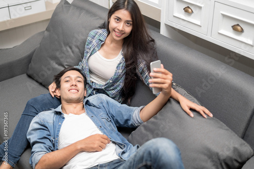 In love new couple at home.Cheerful beautiful young couple selfie on sofa home.Romantict moment.In selective focus.