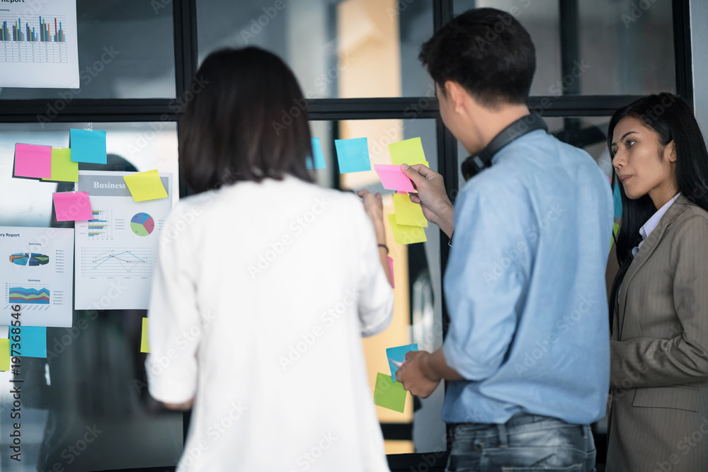 Businesspeople putting their ideas at sticky notes on window. Businesspeople putting their ideas at sticky notes on window.