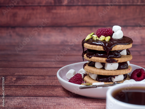 A sweet dessert of chocolate biscuit, raspberry marshmallow and a Cup of coffee on dark background. photo