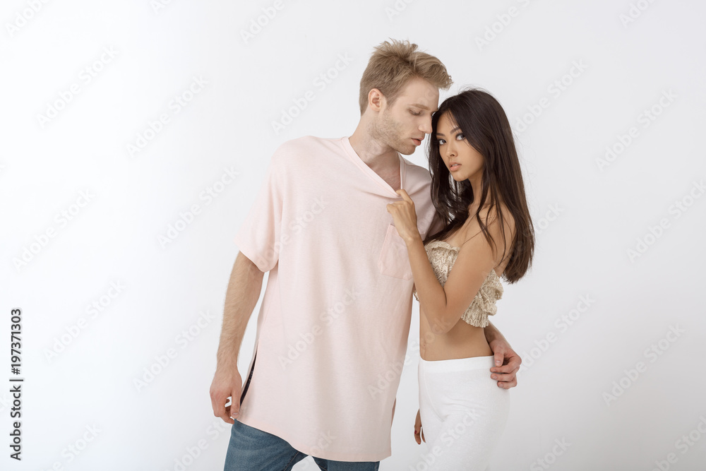 Fashion studio photo of beautifu interracial sexy couple in casual clothes.  Beautiful mixed-race passionate couple posing indoors over white and  looking at camera. Sensual caucasina man hugging Stock Photo | Adobe Stock