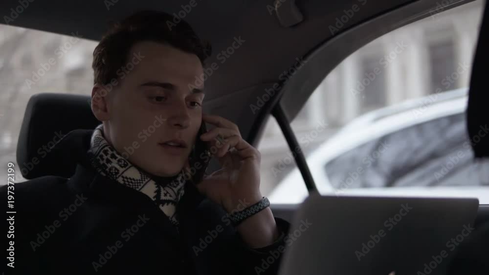 Attractive young guy talking to someone on the phone while riding in a car. Attractive young guy talking to someone on the phone while riding in a car.