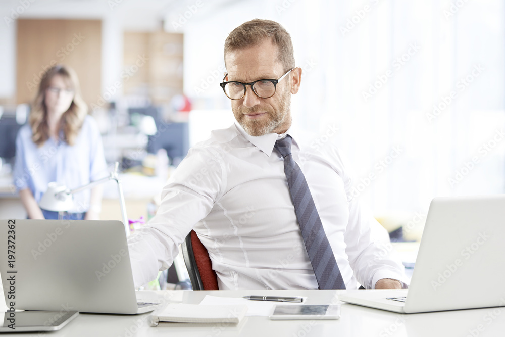 Professional man using laptops. Executive senior financial director businessman sitting at desk and working on laptops. Professional man using laptops. Executive senior financial director businessman sitting at desk and working on laptops.