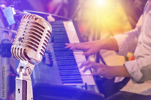 Close up retro microphone with musician playing keyboard synthesizer on band in night concert background photo