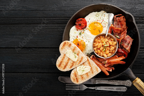 Full english breakfast with egg, sausage and bacon. top view