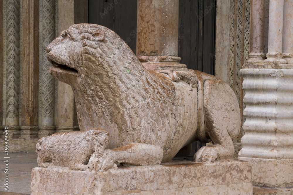 Sculpture of lion with pray in front of Duomo in Modena, Italy