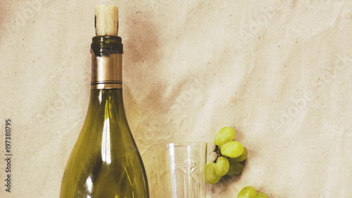 bottle of wine and a wineglass with a white grape brush on a light background photo