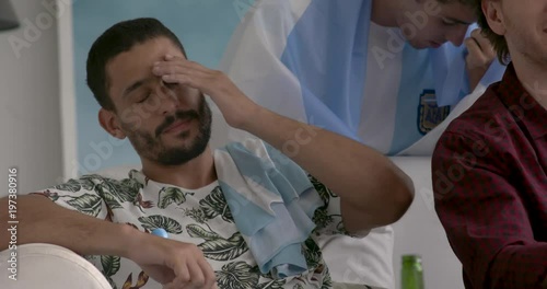 Argentinian football fans expressing disappointment while watching televised match at home, slow motion