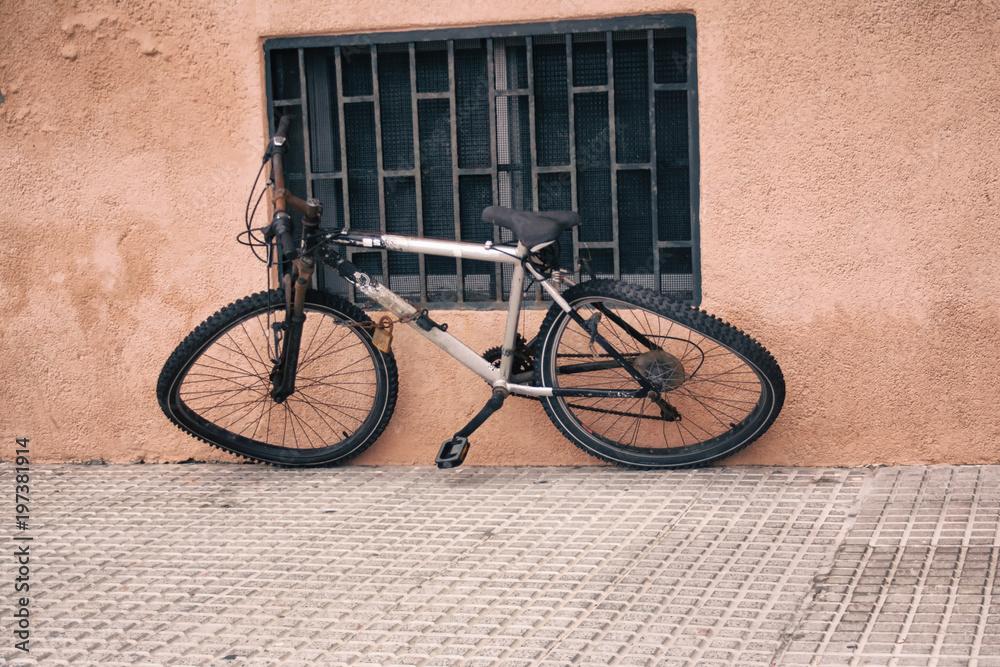 The Bicycle with bent wheels is tied to the window grille