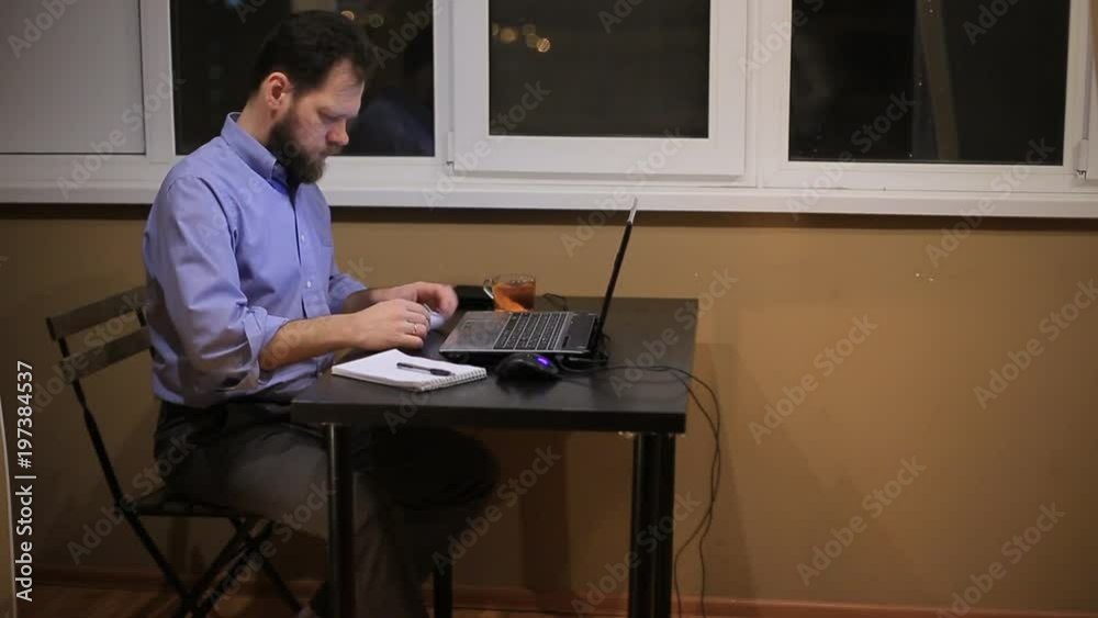a tired businessman works late in the evening with a laptop in the office and composes a financial report.