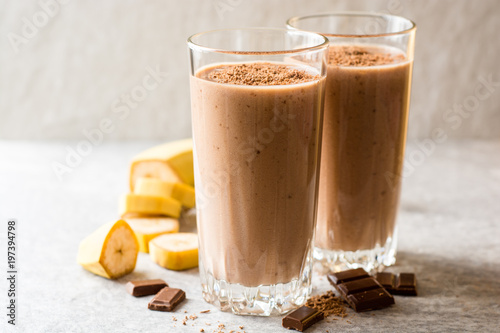 Chocolate banana smoothie in glass on gray stone background