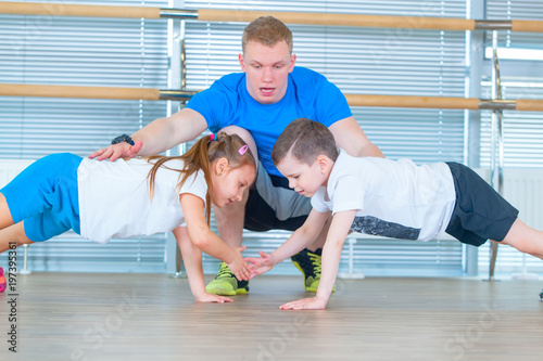 Group of children doing kids gymnastics in gym with teacher. Happy sporty children in gym. bar exercise. plank.