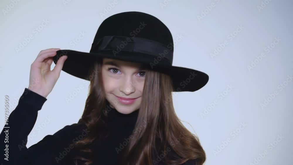 Portrait of happy girl holds a hat and dances at camera on background Portrait of happy girl holds a hat and dances at camera on background
