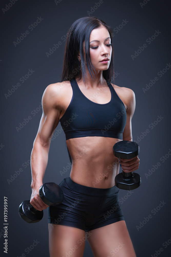 Brutal athletic sexy woman pumping up muscules with dumbbells. The concept of exercise sports, advertising a gym. Brutal athletic sexy woman pumping up muscules with dumbbells. The concept of exercise sports, advertising a gym.