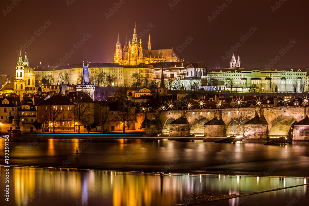 Illuminated city at night. Prague Castle and Charles Bridge 
