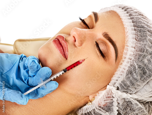 Filler injection for female face. Plastic aesthetic facial surgery and in clinic. Beauty woman giving injections in cosmetology room. Doctor in medical mask. Facelift. photo