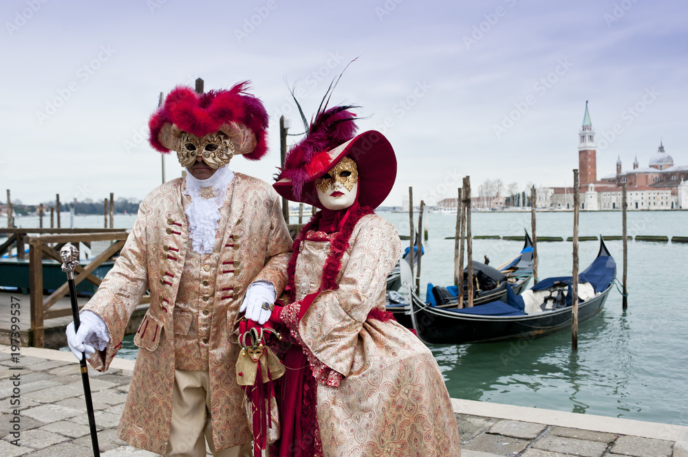 Couple of carnival masks in St. Mark's Square in Venice. In the background the church of San Giorgio.Italy
