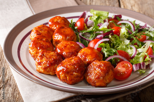 Delicious food: fried chicken meatballs salad of tomato, lettuce and onion close-up on a plate. Horizontal