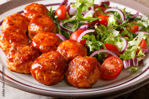 Homemade glazed fried chicken meatballs with fresh salad close-up. horizontal