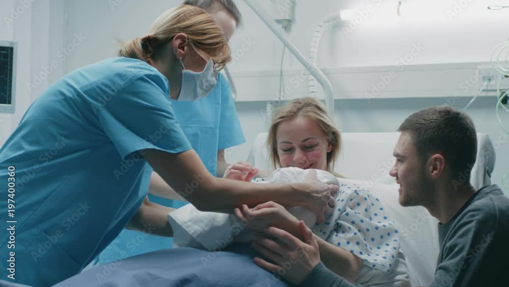 In the Hospital Midwife Gives Newborn Baby to a Mother to Hold, Supportive Father Lovingly Hugging Baby and Wife. Happy Family in the Modern Delivery Ward. Shot on RED EPIC-W 8K Helium Cinema Camera. In the Hospital Midwife Gives Newborn Baby to a Mother to Hold, Supportive Father Lovingly Hugging Baby and Wife. Happy Family in the Modern Delivery Ward. Shot on RED EPIC-W 8K Helium Cinema Camera.