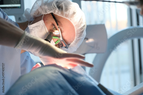 Female dentist in surgical uniform at the clinic while performing surgery for the patient