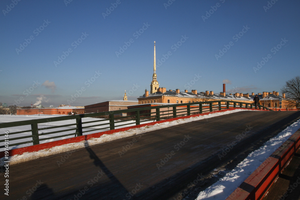 Winter day in St. Petersburg. The main attraction of St. Petersburg fortress in the city center - Peter and Paul fortress. The spire of Peter and Paul Cathedral shines in the sun.