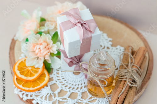 Made at home from orange oil with cinnamon perfume in a glass jar. Slices of dried orange  dried cinnamon and flowers. Gift box with jewelry charm bracelet is on the table. Present for every woman.