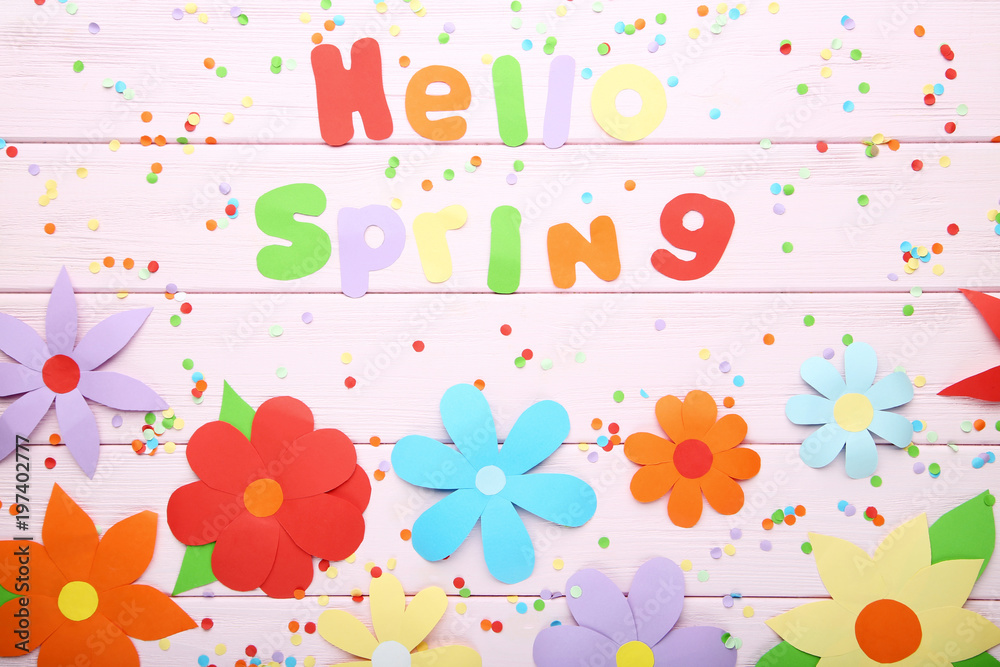 Inscription Hello Spring with paper flowers on wooden table Inscription Hello Spring with paper flowers on wooden table