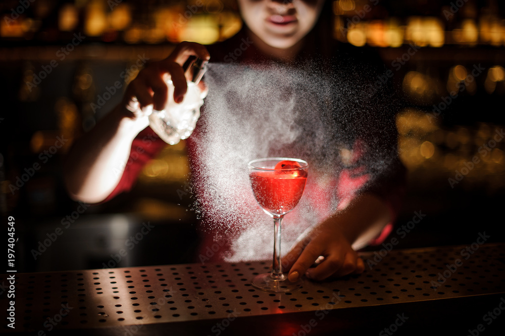 Female bartender sprinkling a cocktail glass filled with tasty Aperol syringe summer cocktail with a peated whisky