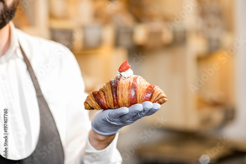 Holding delicious croissant with raspberry in the bakery store