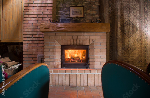 Moody fireplace indoor, with two green armchairs, and home-like ornaments around.