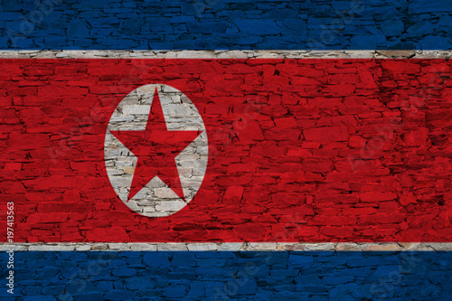 An image of the North Korea flag painted on a brick wall in an urban location