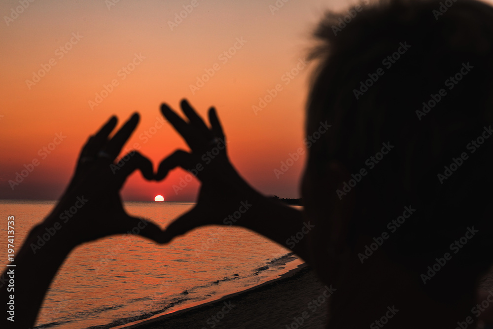 Close up of heart made by female hands background the sunset sea. Vintage effect style pictures.