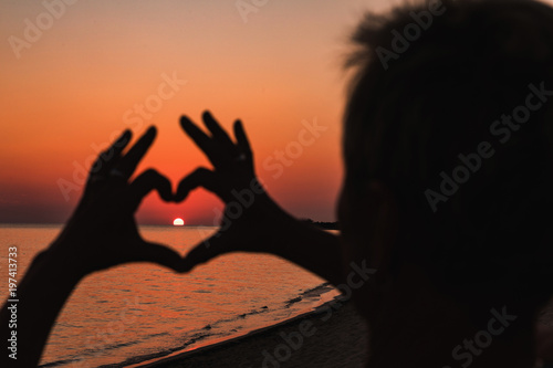 Close up of heart made by female hands background the sunset sea. Vintage effect style pictures.